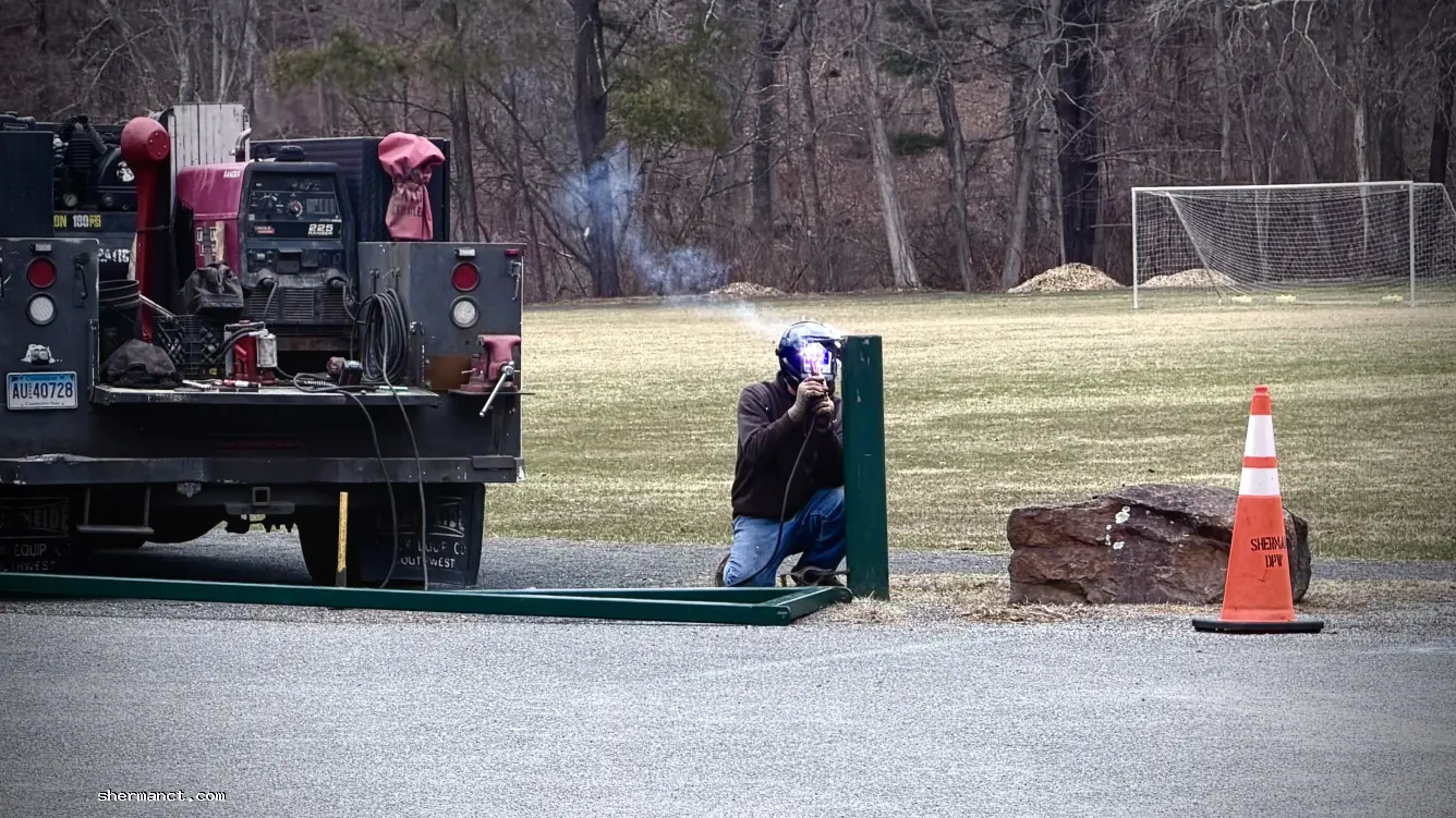<strong>Mending Veterans Field:</strong> A local tradesman welds the broken safety gate back together, a sign of spring and a reminder of the blue-collar backbone that keeps Sherman running.