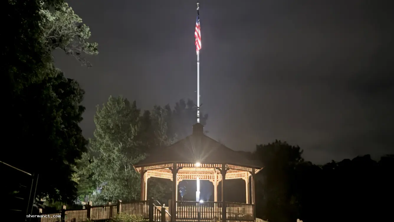 <strong>Proper Protocol:</strong> The American flag flies proudly over the illuminated gazebo, signaling a pause in the nightly routine of the town's flag vigilante.